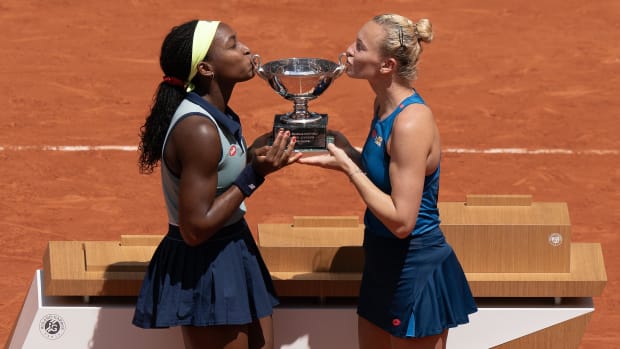 Gauff and Siniakova kiss the women's doubles French Open trophy.